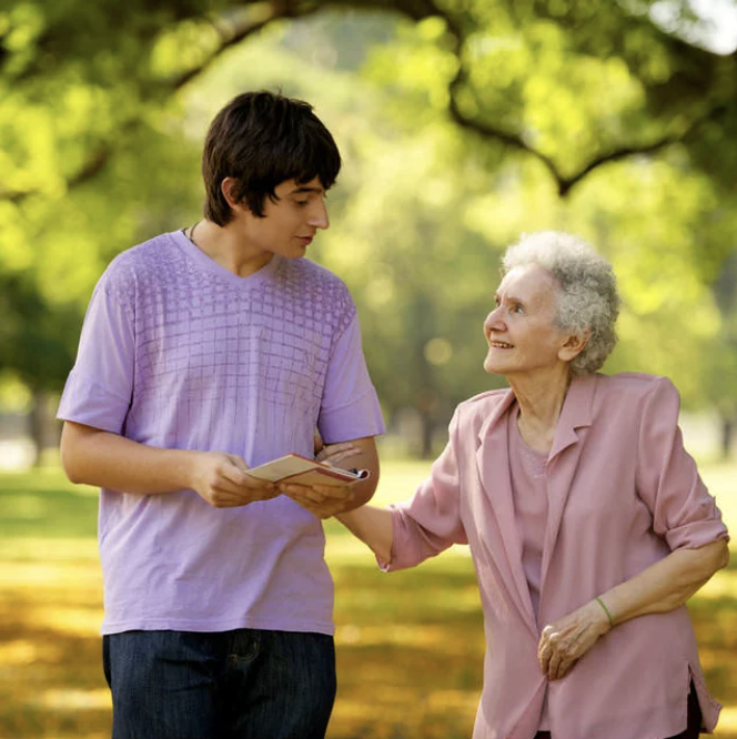 A young man and an older woman walking together and talking in a park